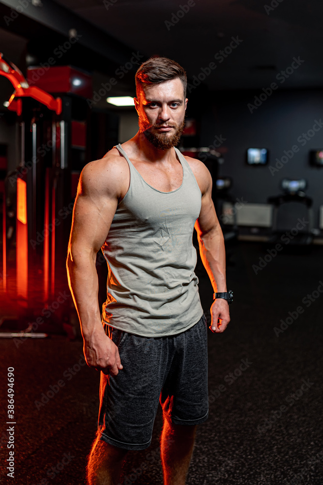 Athletic guy is looking to the camera. Big muscles, strong abs. Handsome sportive model on the gym b