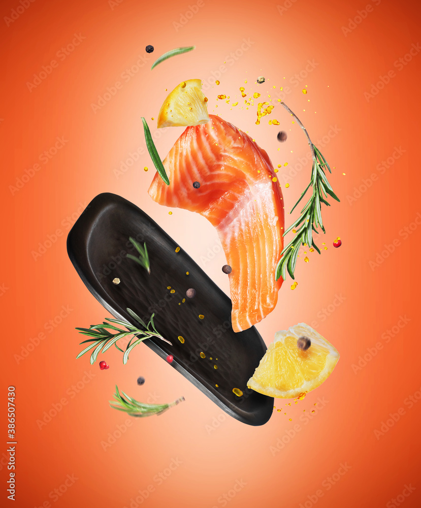 Slice of fresh salmon with spices and lemon in the air on a red background