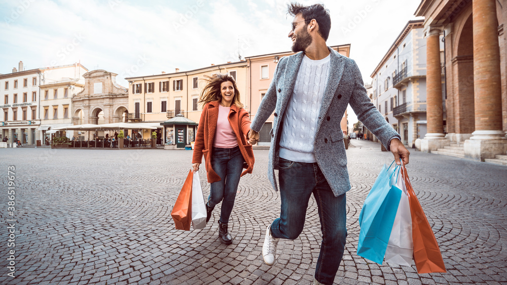 Happy couple of tourists walking in the city holding shopping bags - Boyfriend and girlfriend in lov