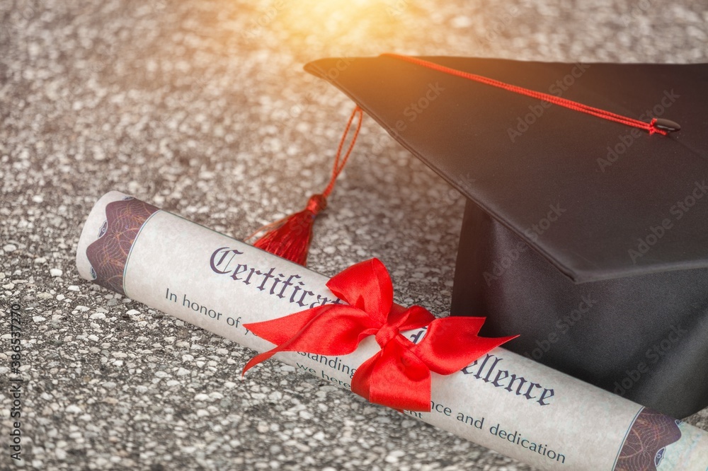 Graduation black hat and diploma on road