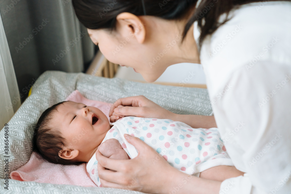 portrait of asian baby feeling comfortable after changing diaper and laughing to her mother happily.