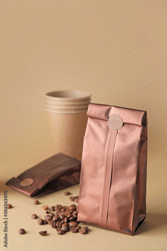 Blank coffee bags and cup on color background