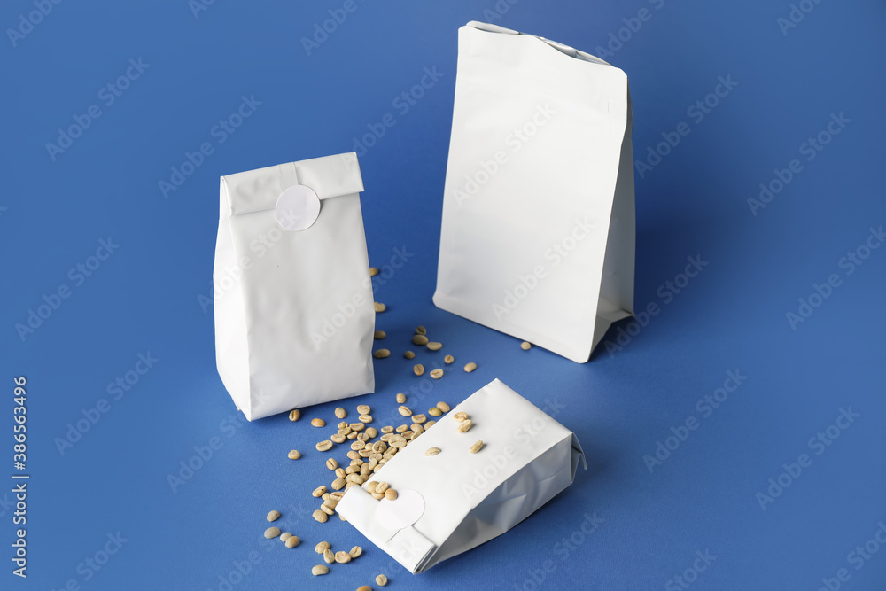 Blank coffee bags on color background