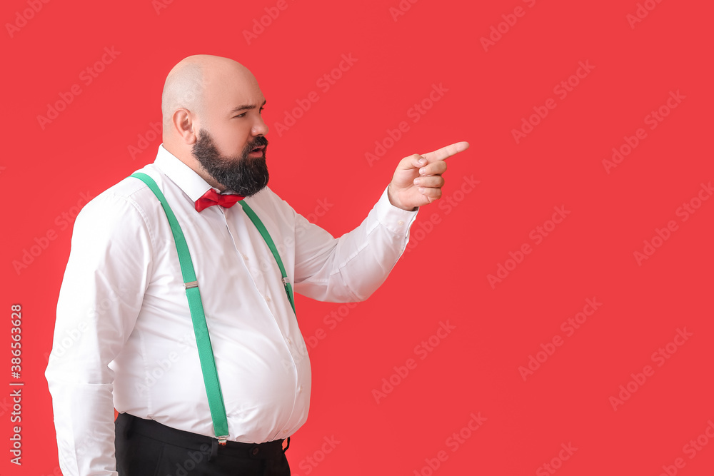 Overweight businessman pointing at something on color background