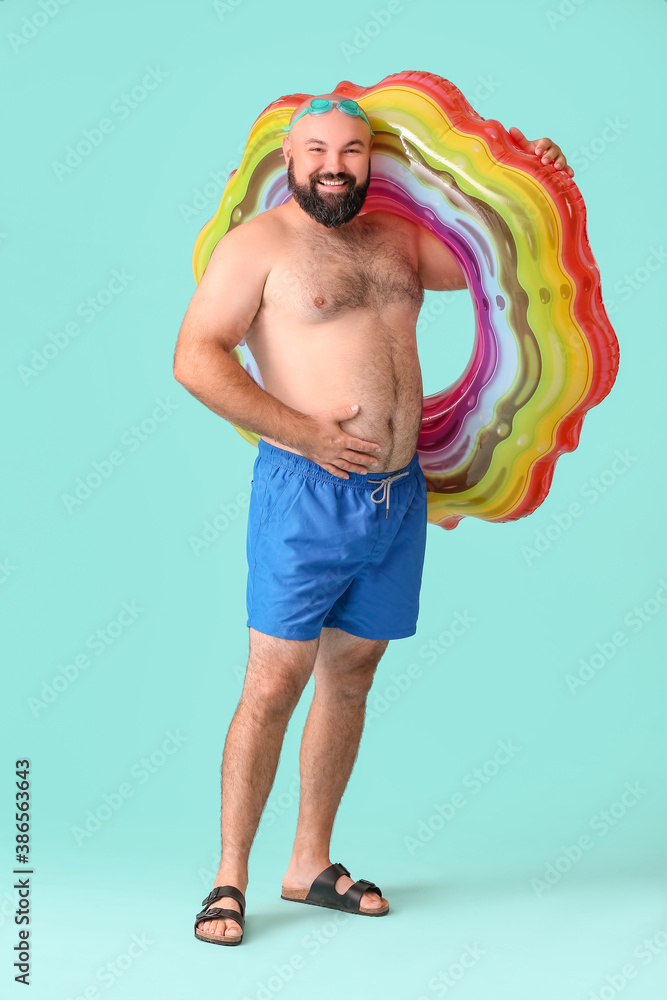 Overweight man with inflatable ring on color background