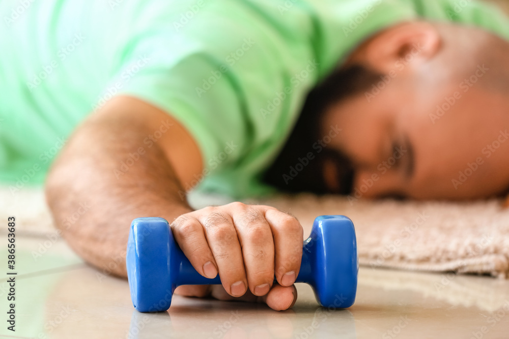 Exhausted overweight man lying on floor after training at home. Weight loss concept