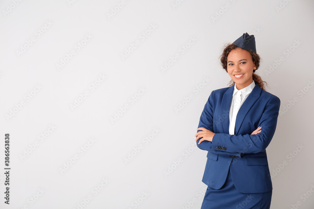 Beautiful African-American stewardess on grey background