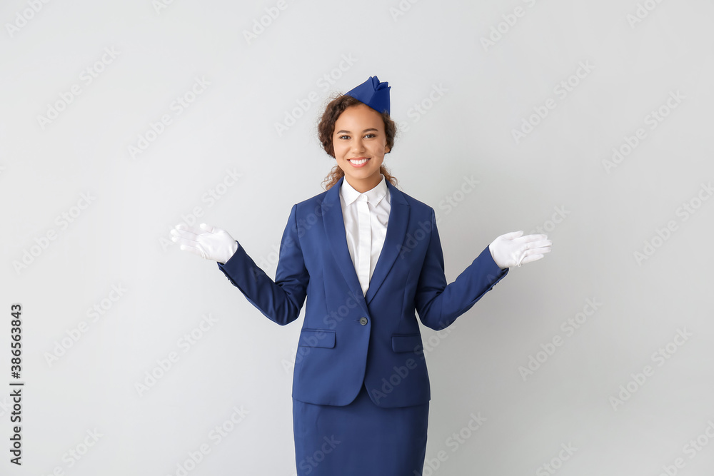 Beautiful African-American stewardess on grey background