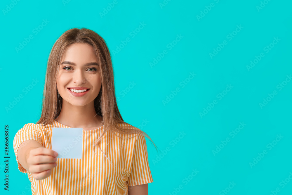 Young woman with small blank paper sheet on color background