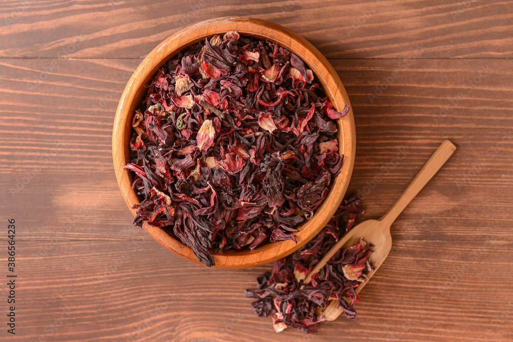 Bowl and scoop with dry hibiscus tea on table