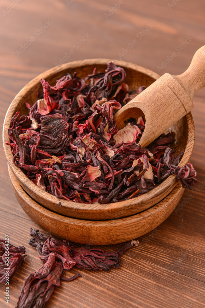 Bowl and scoop with dry hibiscus tea on table