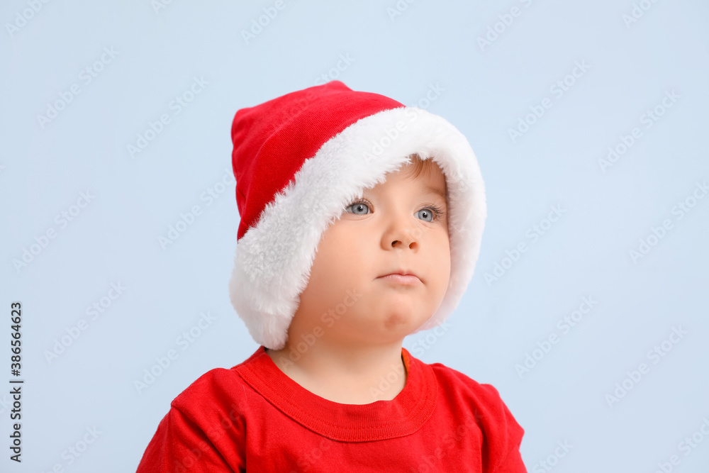 Cute little baby in Santa hat on color background