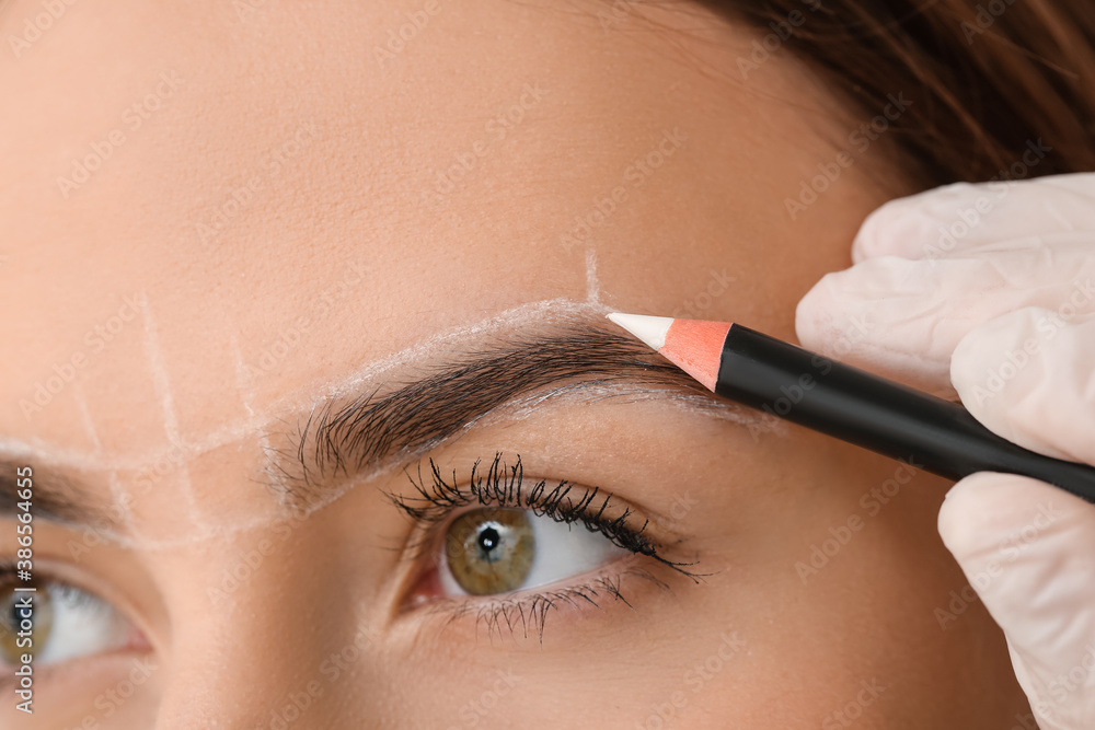 Young woman undergoing eyebrow correction procedure in beauty salon, closeup