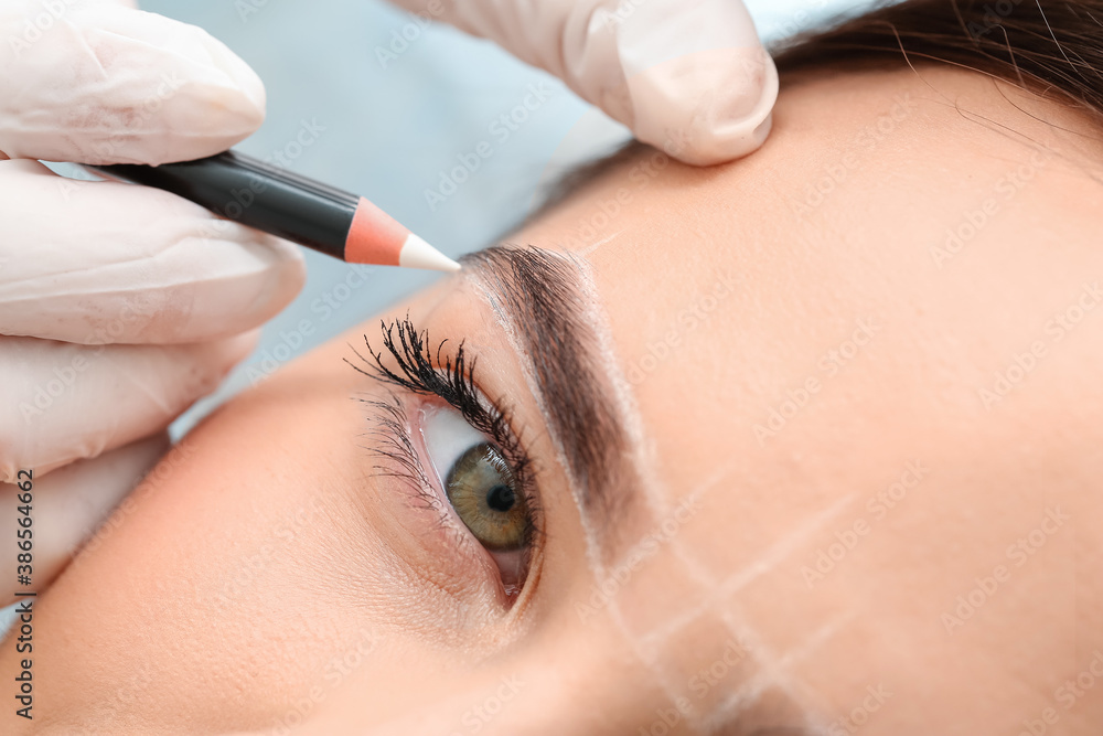 Young woman undergoing eyebrow correction procedure in beauty salon, closeup