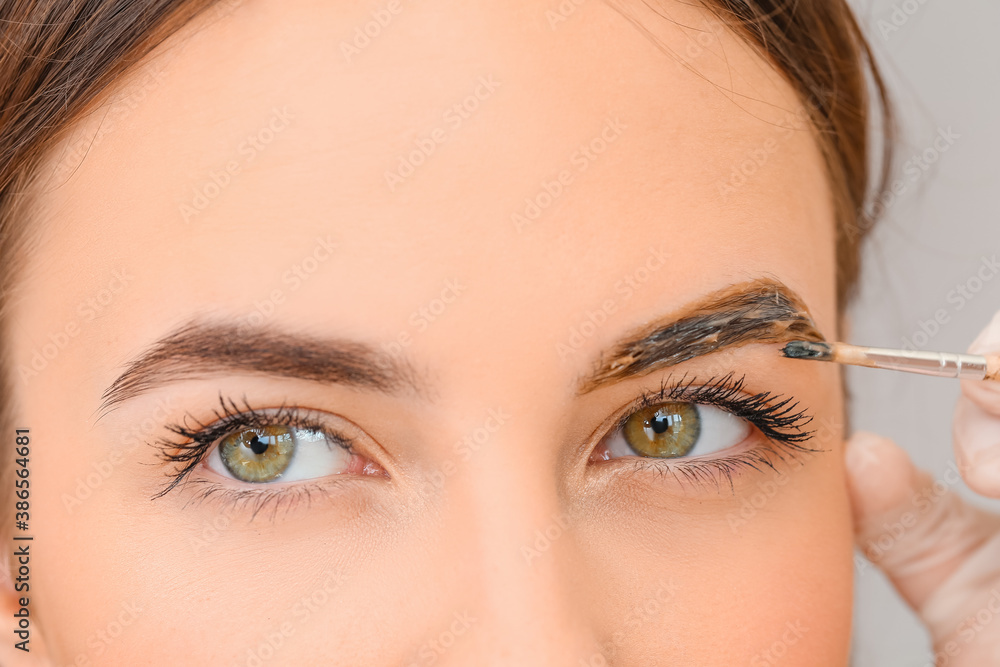 Young woman undergoing eyebrow correction procedure in beauty salon, closeup