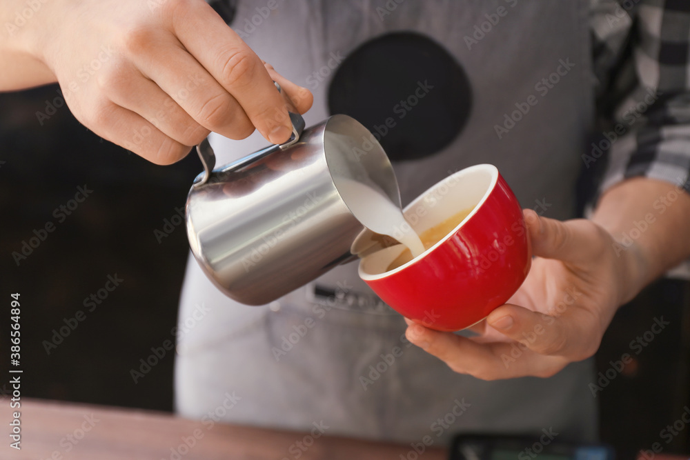 Barista making hot coffee in cafe, closeup