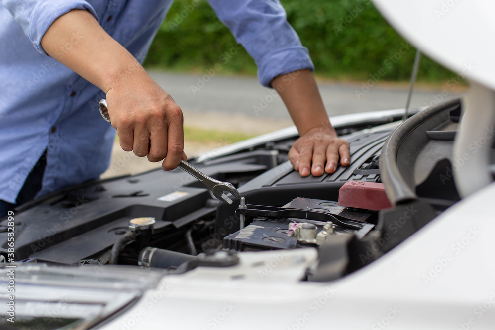 Mans hand is causing his car to crash by using a wrench at various points, car insurance concept.