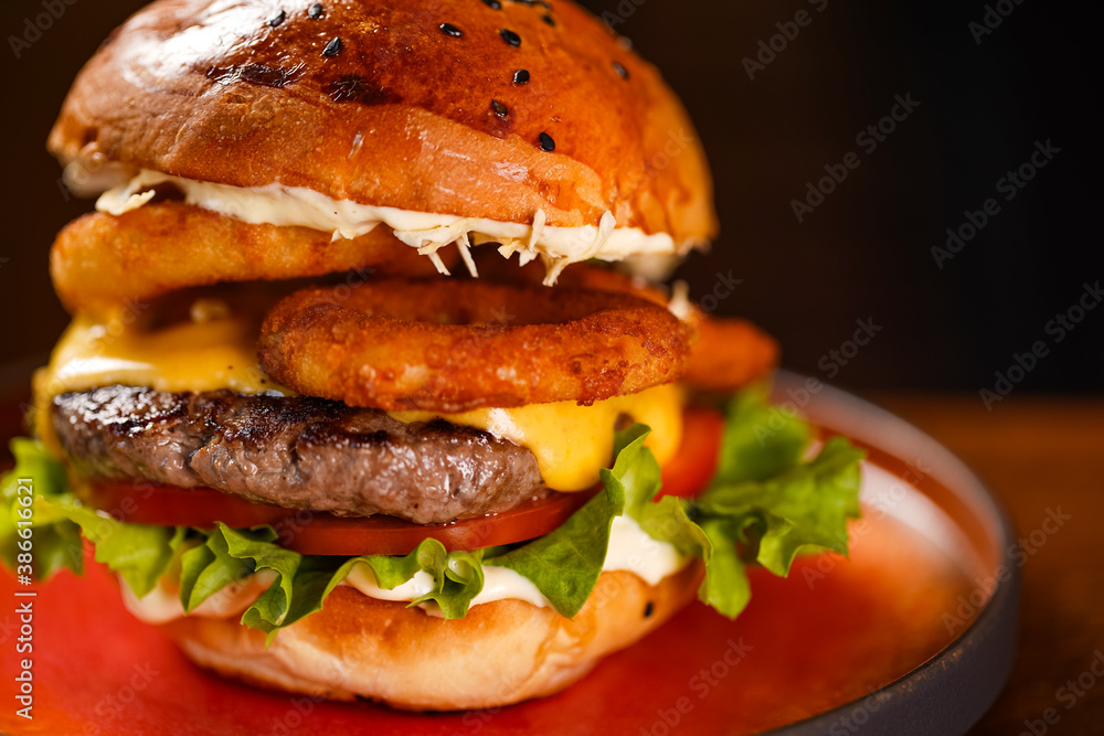 Beef burger with onion rings, cheese and sauce.