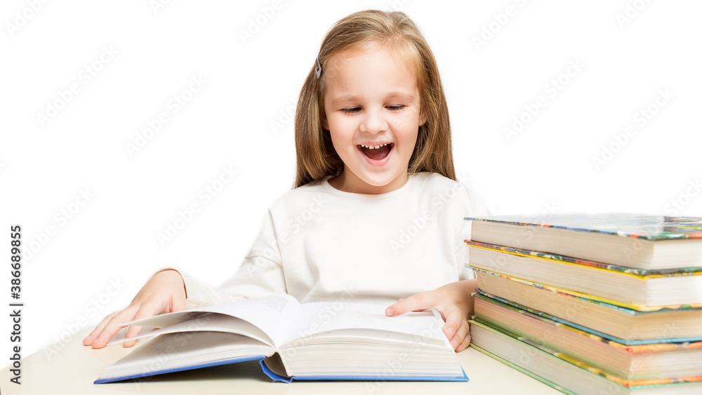 little cheerful girl sitting at the table and reads a books laughs on a white background.