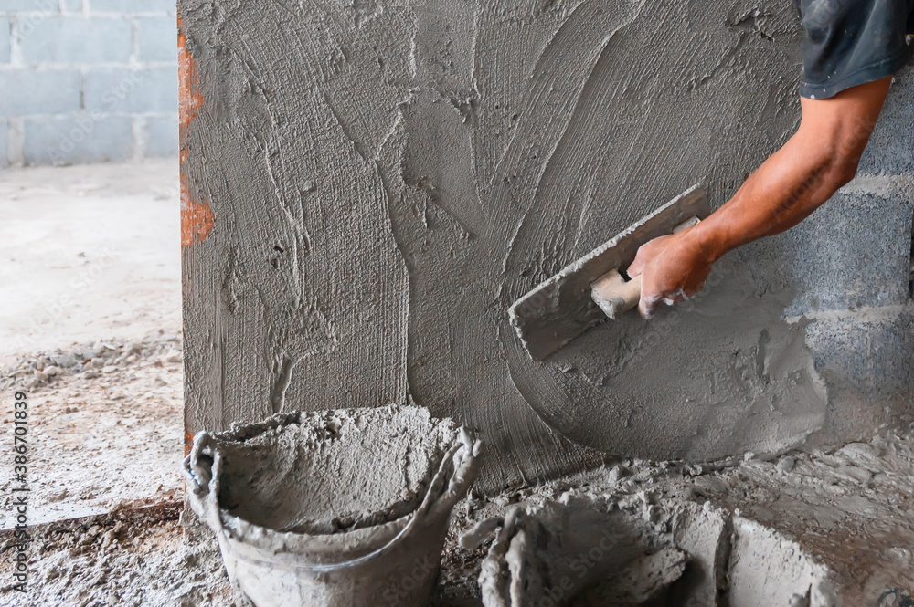 closeup hand of worker plastering cement at wall in construction site