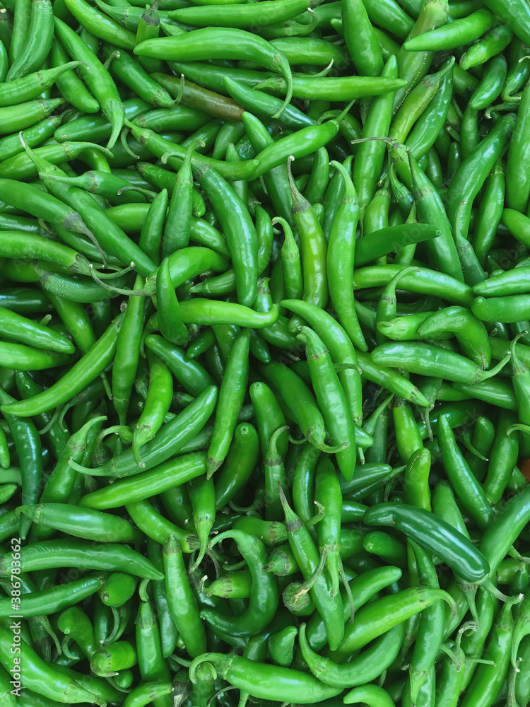 High angle close-up view of fresh green serrano chili peppers displayed for sale at a grocery market