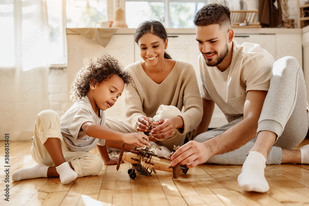 Diverse parents playing with son in kitchen.