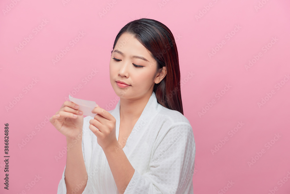 Closeup of beautiful asian girl model with natural face makeup looking at oil absorbing tissue