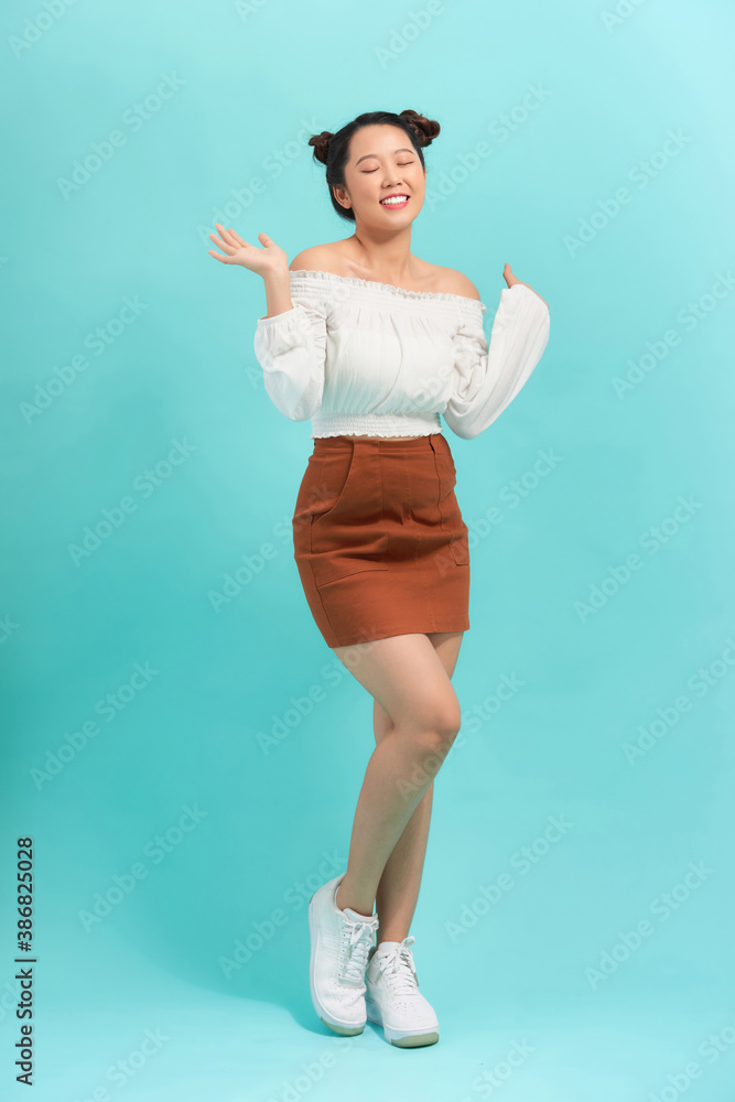 Full length portrait of a cheerful beautiful girl having fun isolated over blue background