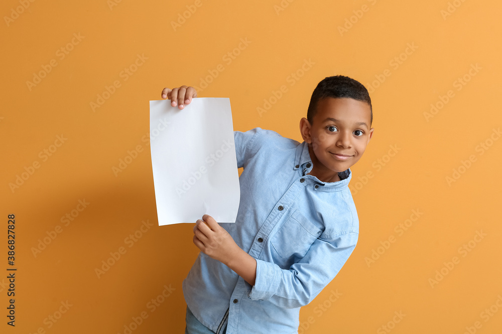 Little African-American boy with blank paper sheet on color background