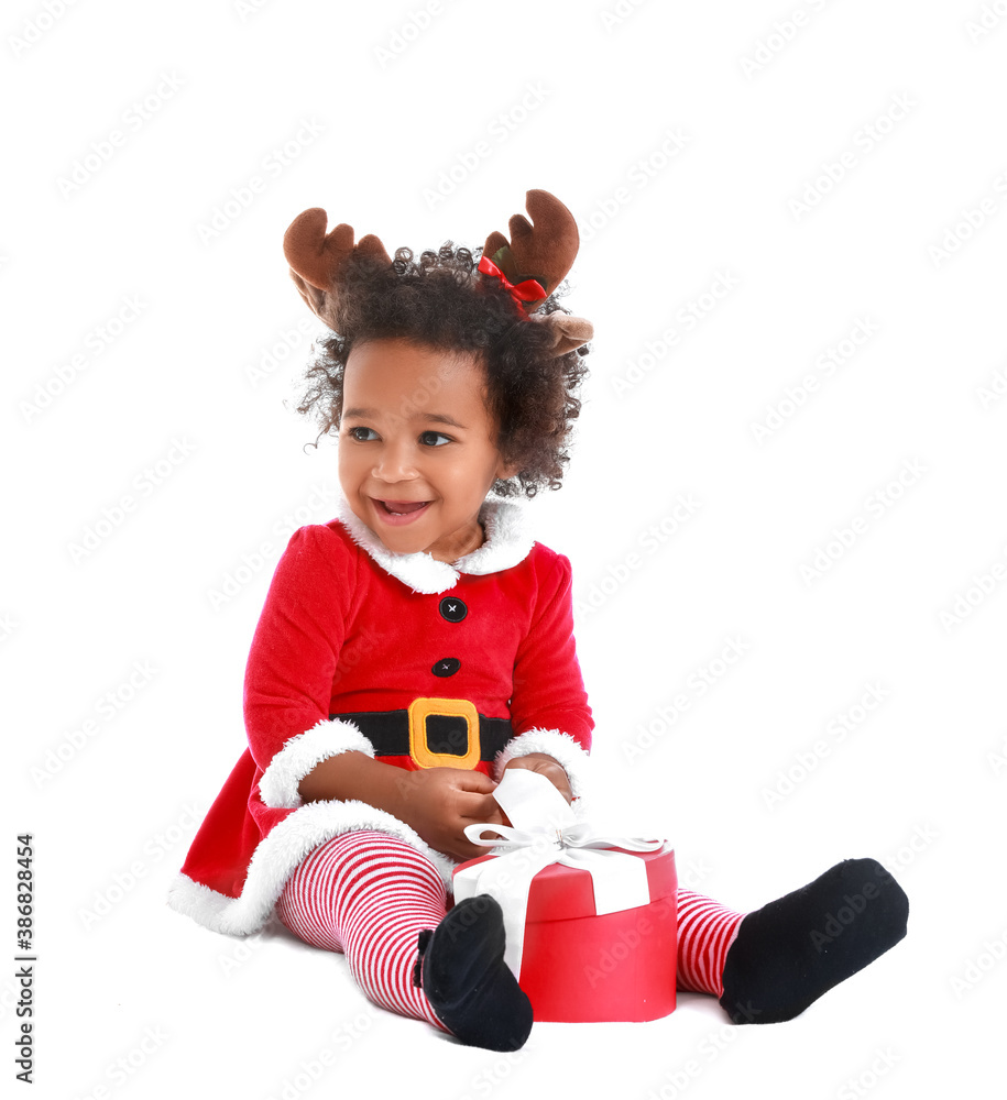 Cute African-American baby girl dressed as Santa and with Christmas gift on white background