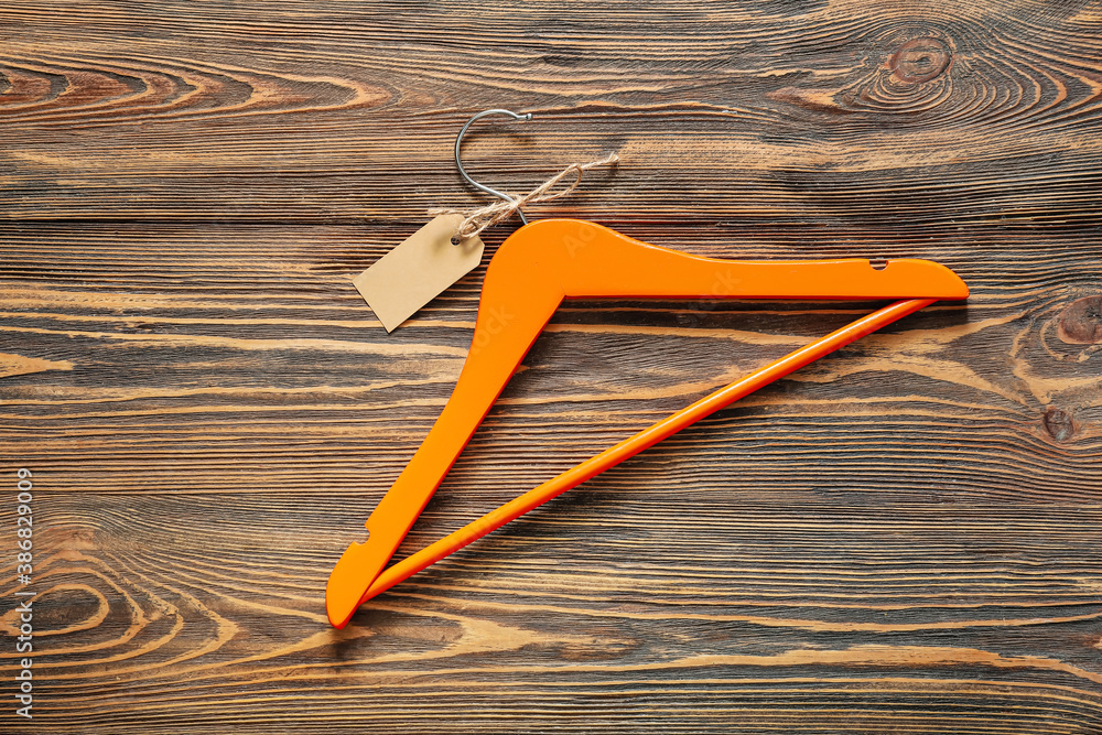 Clothes hanger with tag on wooden background