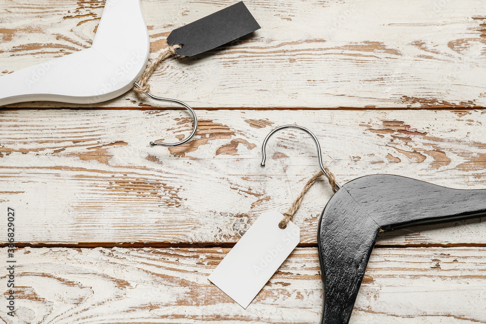 Clothes hangers with tags on wooden background