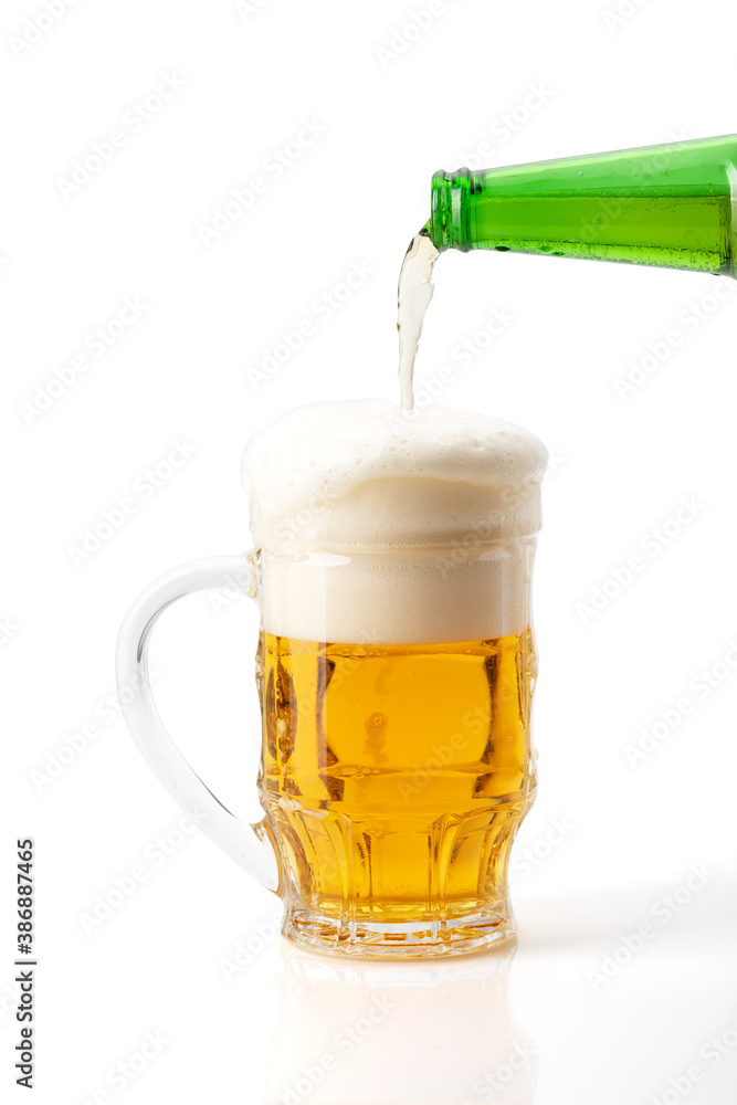 Beer is poured into a glass on a white background.