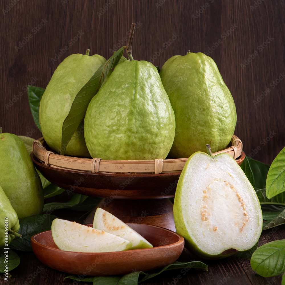 Close up of delicious guava with fresh green leaves on wooden background.