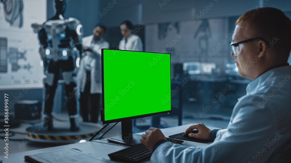 In Development Laboratory: Chief Analyst Uses Computer with Green Screen Template, Scientists and En