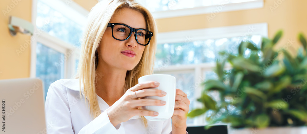 Happy young woman drinking coffee in an office