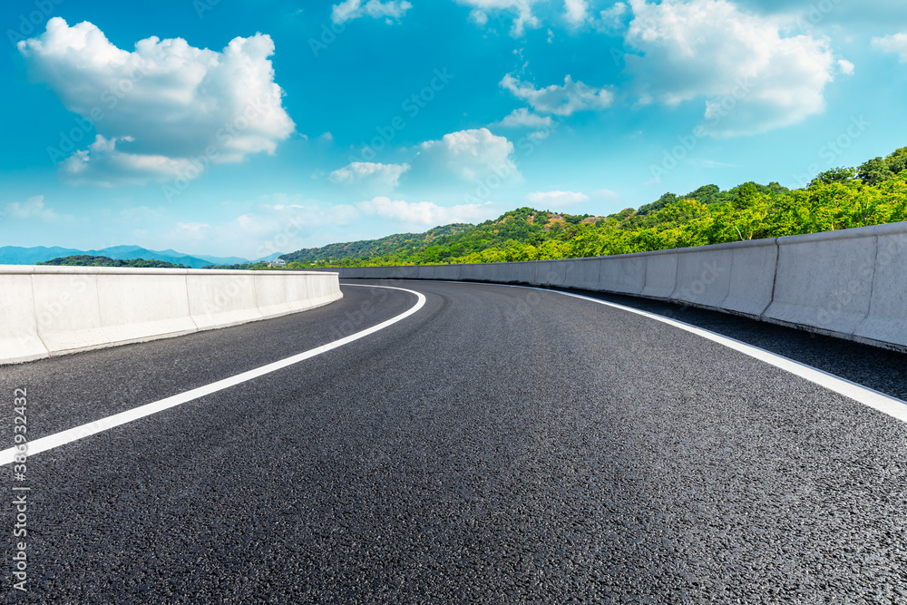 Asphalt road and green mountains under blue sky.