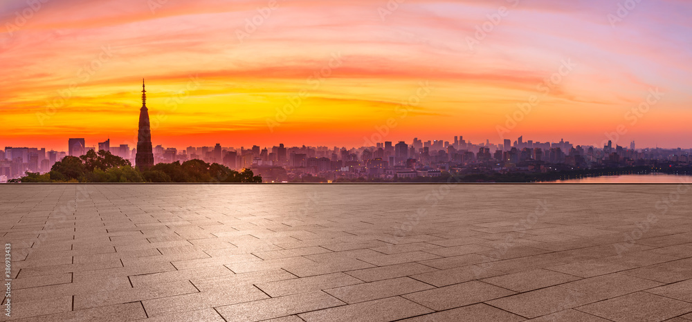 Wide square floor and city skyline with buildings in Hangzhou at sunrise.