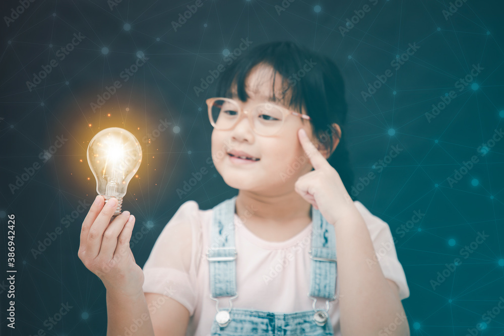 Asian Little girl holding light bulb in the black background, ideas with innovative technology and E