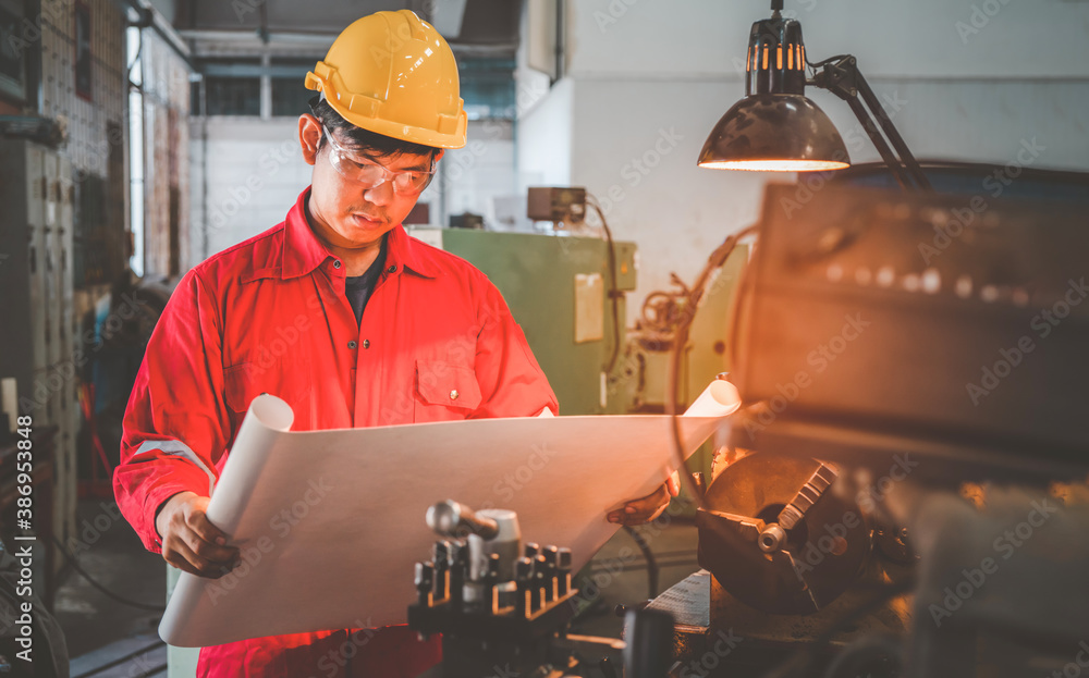 Asian man foreman working with drawing NC Lathe machinery with safety uniform concept smart manufact