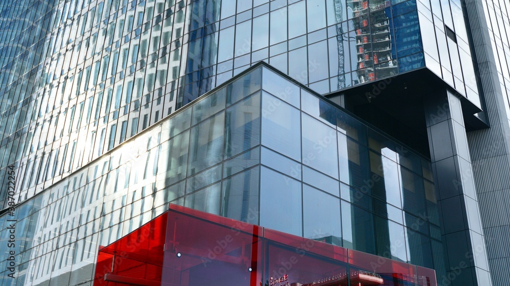 Blue curtain wall made of toned glass and steel constructions under blue sky. A fragment of a buildi