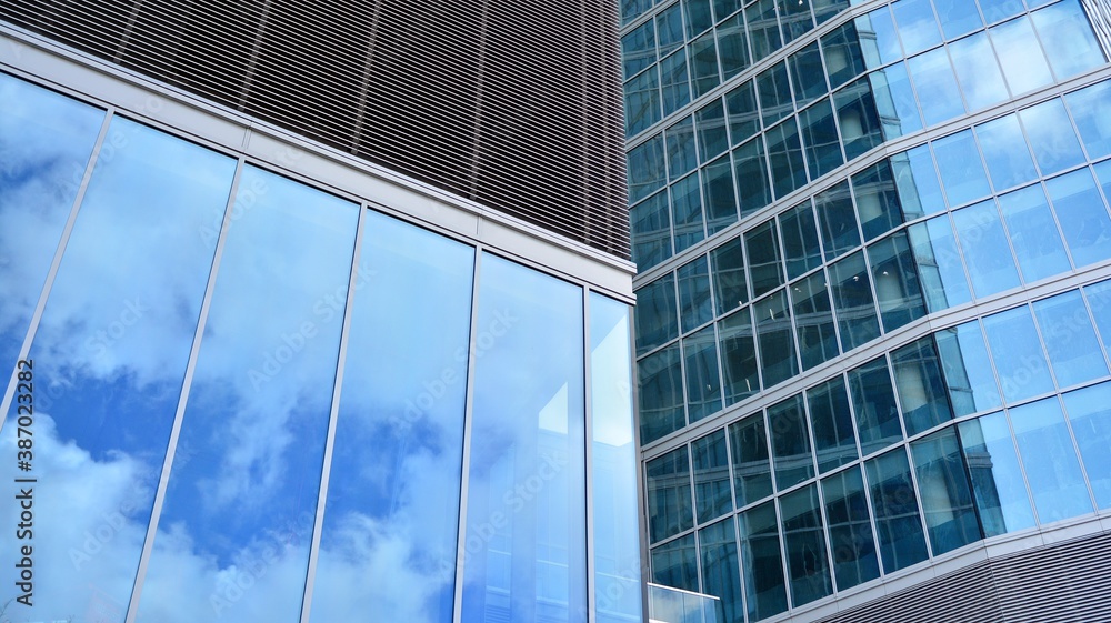 Blue curtain wall made of toned glass and steel constructions under blue sky. A fragment of a buildi