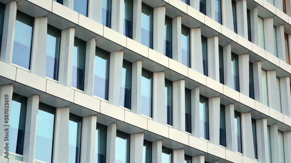 Blue curtain wall made of toned glass and steel constructions under blue sky. A fragment of a buildi