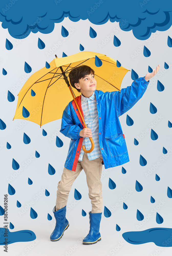 Cute little boy in raincoat and with umbrella on light background with drawn cloud and drops