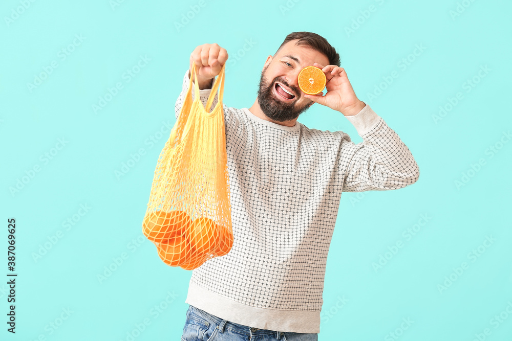 Man with oranges on color background