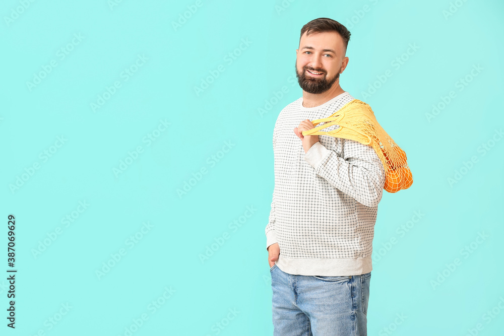 Man with oranges on color background