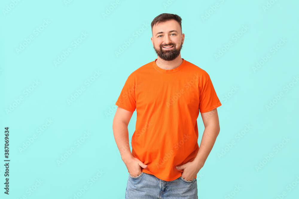 Handsome man in orange t-shirt on color background