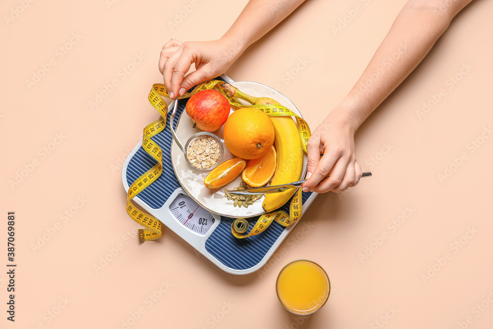 Female hands with fresh products, scales and measuring tape on color background. Diet concept