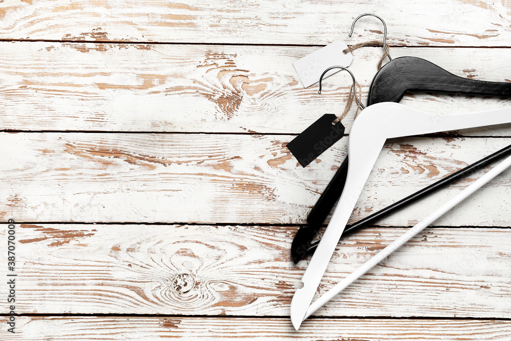 Clothes hangers with tags on wooden background