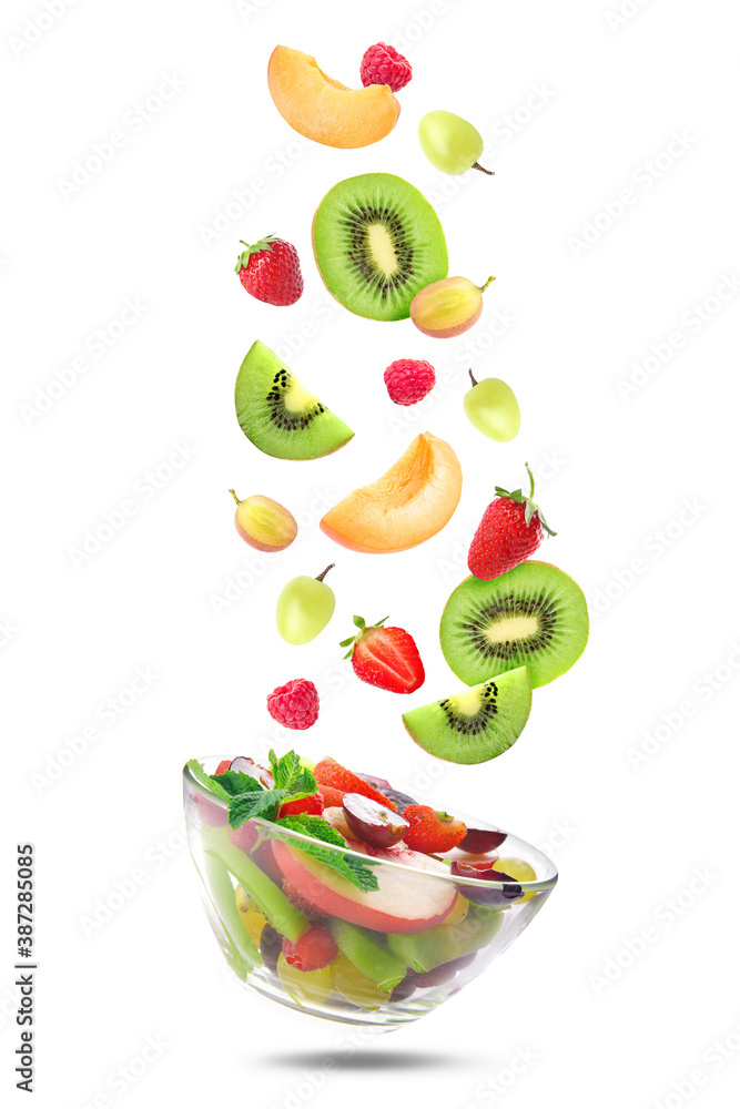 Delicious fruit salad in bowl and flying ingredients on white background